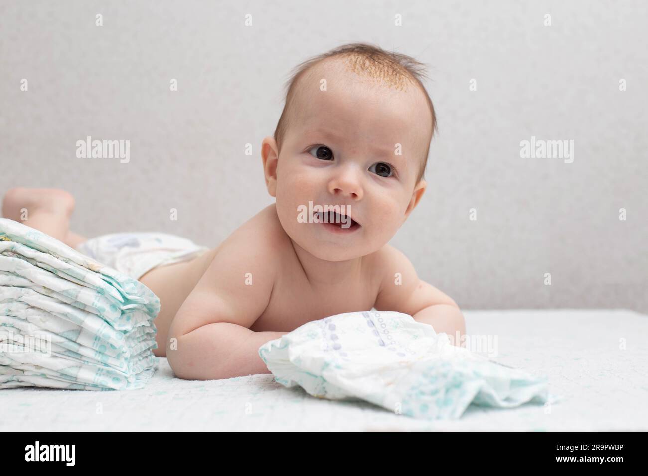 A little boy at the age of 5 months lies in a diaper on a white