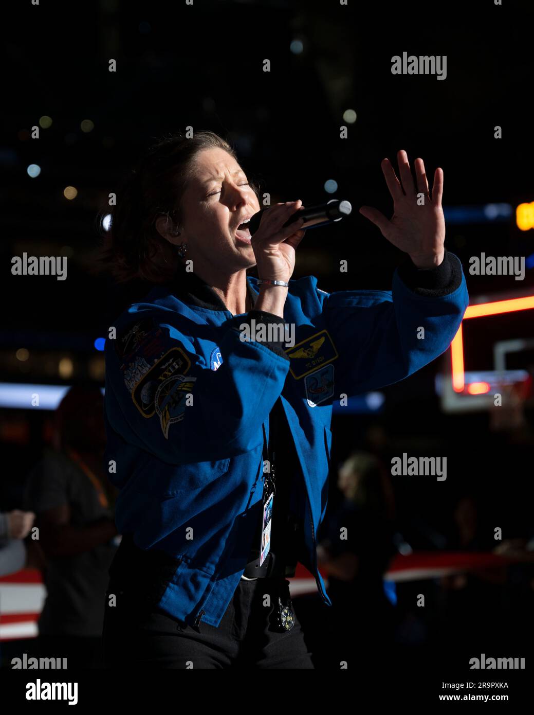 . jsc2023e018213 (April 3, 2023) – NASA astronaut Tracy Caldwell Dyson sings the national anthem before the NCAA Men’s Final Four national championship game at NRG Stadium in Houston, where the Artemis II astronauts were introduced. The crew is comprised of Commander Reid Wiseman, Pilot Victor Glover, and Mission Specialists Christina Koch and Jeremy Hansen. The four astronauts will venture around the Moon on Artemis II, the first crewed mission on NASA’s path to establishing a long-term presence at the Moon for science and exploration through Artemis. Stock Photo