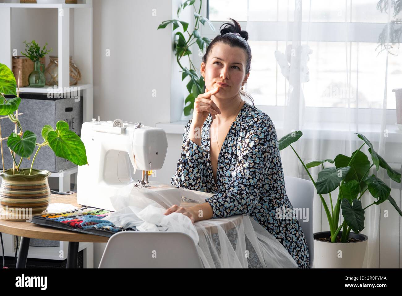 Woman thinking, dreaming and sews tulle on an electric sewing machine