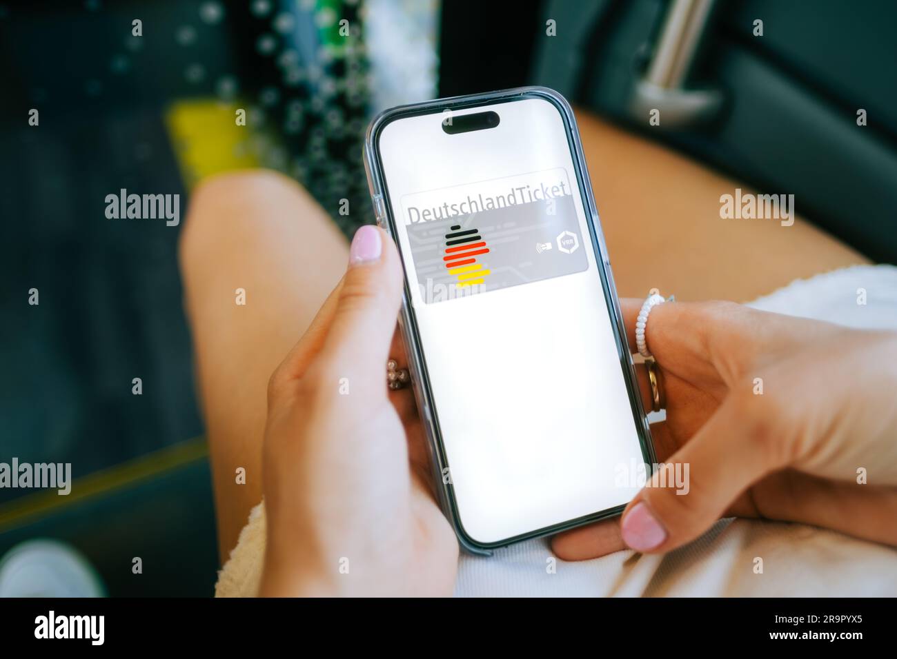 DeutchlandTicket on mobile phone screen, woman holding iPhone with new German subscription travel card. Stock Photo