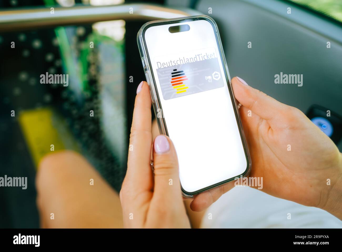 DeutchlandTicket on mobile phone screen, woman holding iPhone with new German subscription travel card. Stock Photo