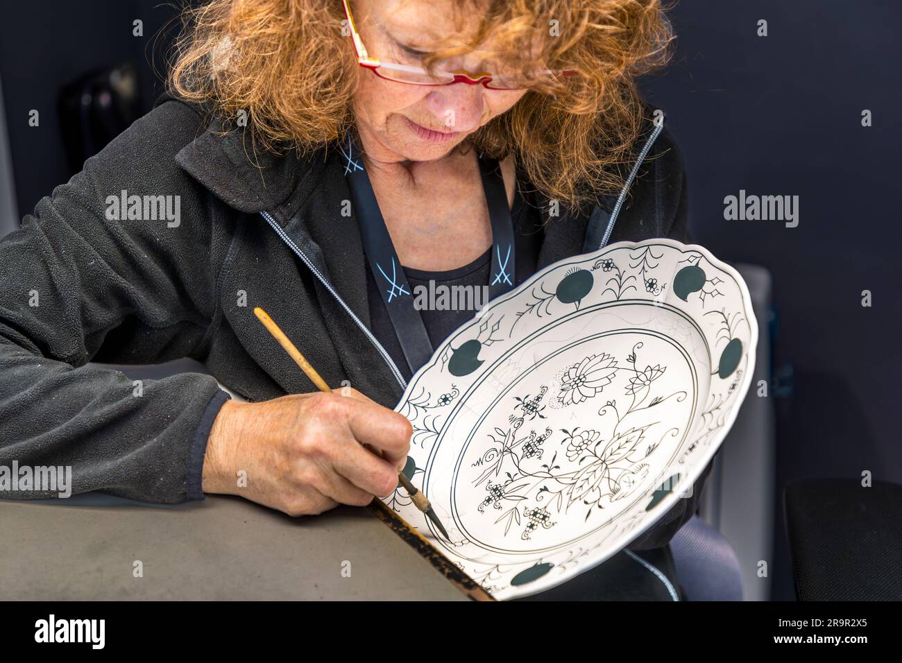 Craftswoman at the Porcelain Museum of the Porcelain Foundation Meissen. Underglaze painting with cobalt metal oxide in the Porcelain Museum in the Porcelain Foundation Meissen, Germany Stock Photo