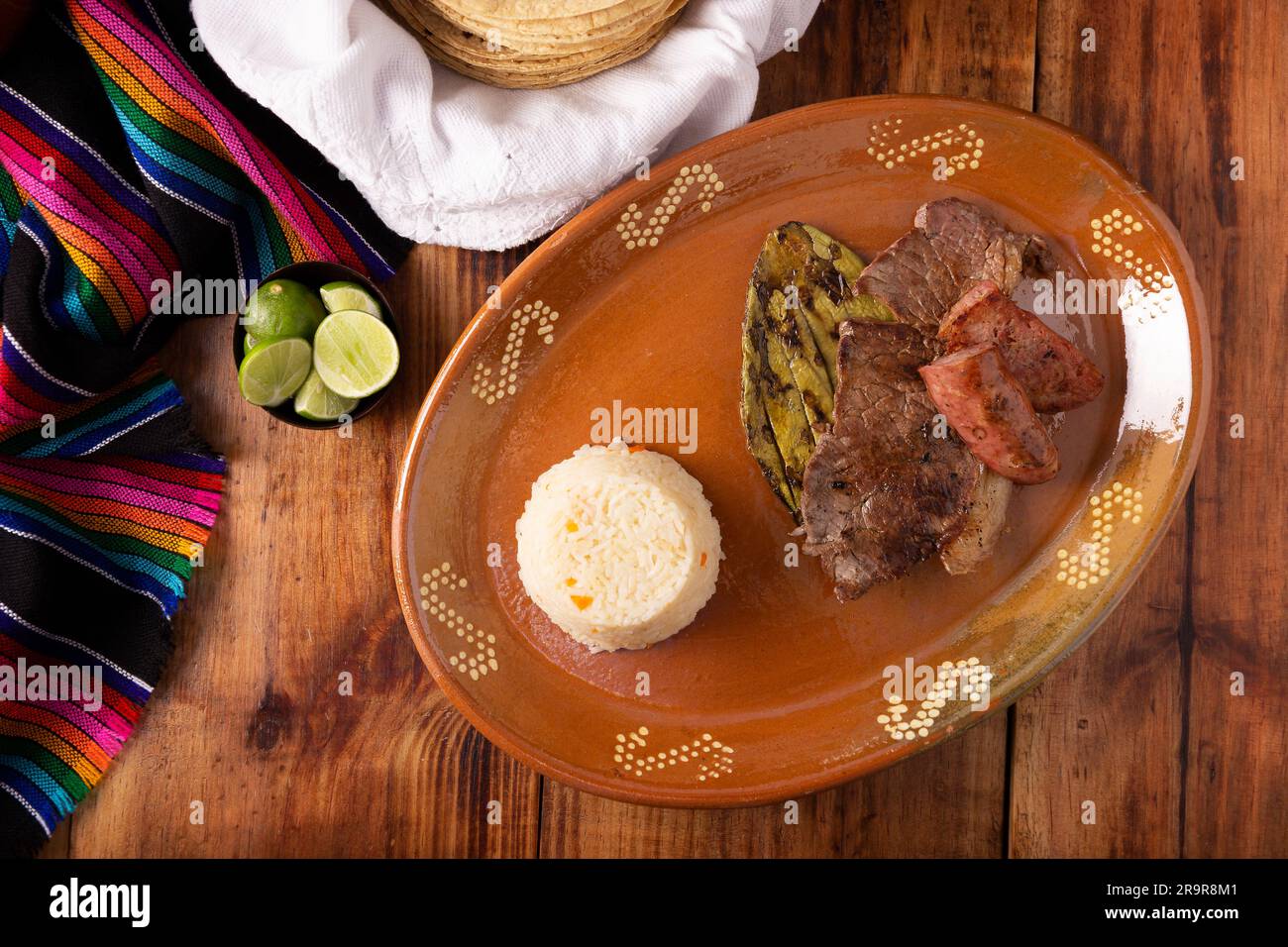 Roasted meat with roasted nopal cactus and pork sausage called chorizo, accompanied by white rice served in a typical Mexican clay plate. Stock Photo