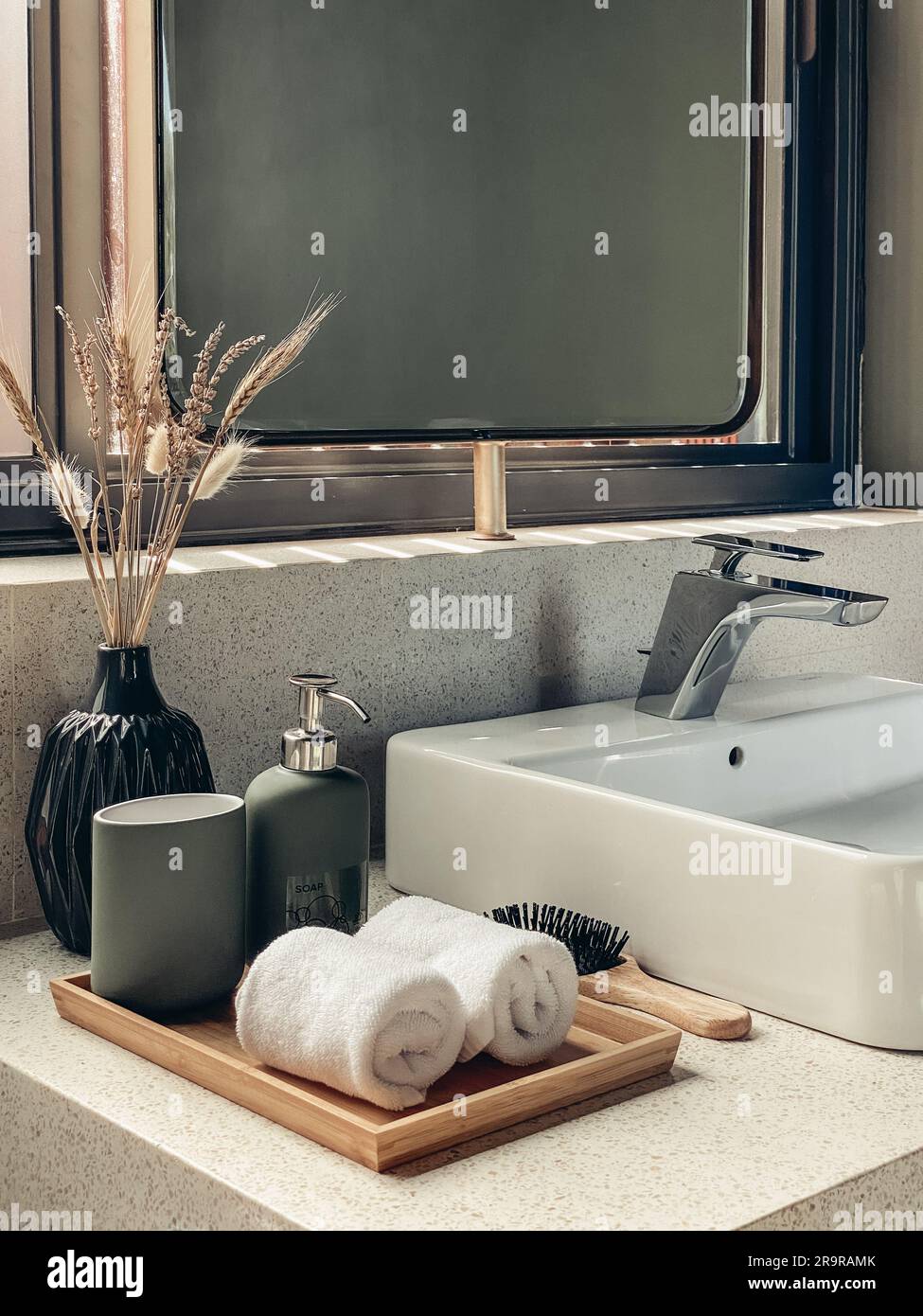 Two hand towels in the bathroom with liquid soap dispenser on bamboo tray and hair brush Stock