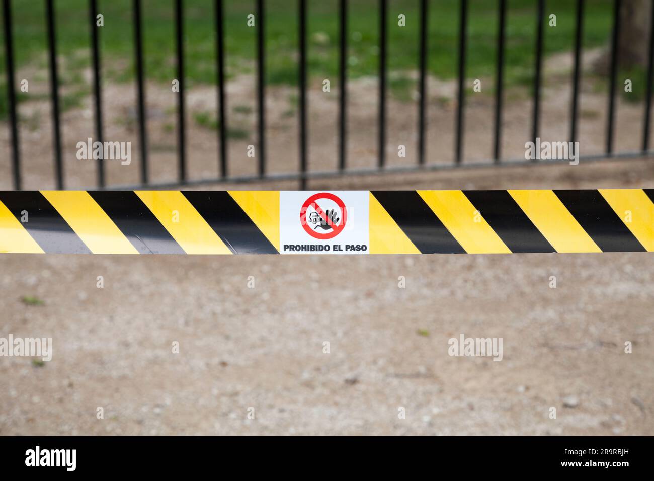 Yellow and black striped tape with a no entrance sign with written bellow in spanish 'Prohibido el paso' meaning in Englist 'No entry'. Stock Photo