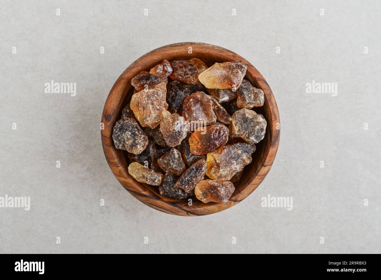 Large caramelized sugar in wooden bowl on concrete background. Top view Stock Photo