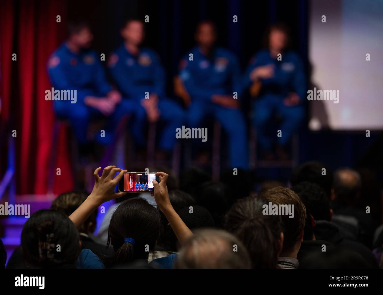 Artemis II Crew at GSFC. A member of the audience takes a video as CSA (Canadian Space Agency) astronaut Jeremy Hansen, and NASA astronauts Reid Wiseman, Victor Glover, and Christina Hammock Koch, answer questions during an employee engagement event Friday, May 19, 2023, at NASA’s Goddard Space Flight Center in Greenbelt, Md. Wiseman, Glover, Hammock Koch, and Hansen, who will fly around the Moon on NASA’s Artemis II flight test, visited Washington to discuss their upcoming mission with members of Congress and others. Stock Photo