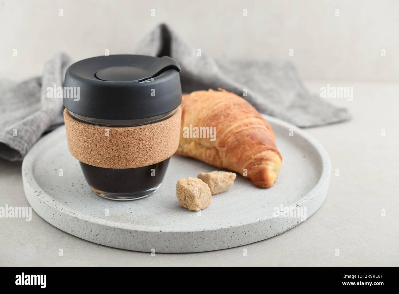 https://c8.alamy.com/comp/2R9RC8H/coffee-to-go-in-reusable-travel-mug-made-from-glass-and-cork-band-with-croissant-on-tray-zero-waste-sustainable-lifestyle-concept-2R9RC8H.jpg