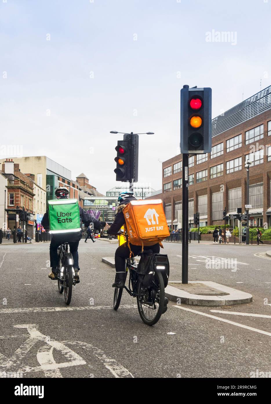 Uber Eats and Just Eat cucle couriers at traffic lights in Newcastle upon Tyne, UK Stock Photo