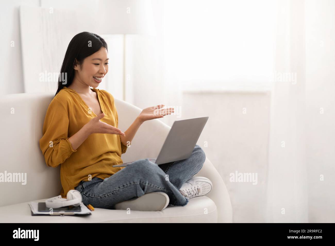 Positive asian woman working from home, using laptop Stock Photo
