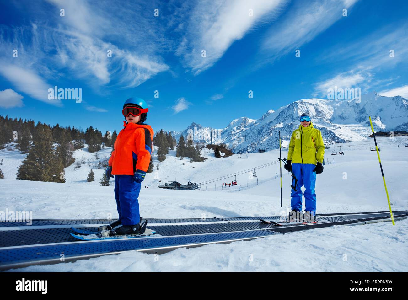 Little boy and a instructor go up on the ski moving walkway Stock Photo