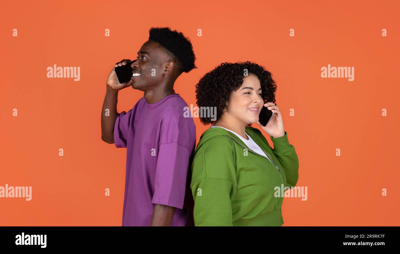 Smiling young interracial couple talking on mobile phone Stock Photo