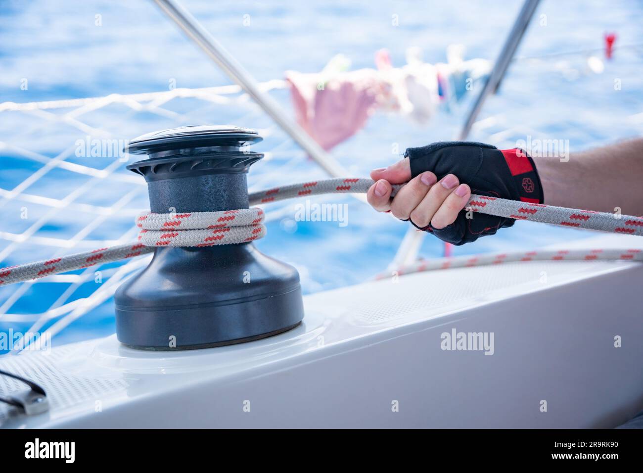 Mans hand pulling winch rope on sailing boat Stock Photo