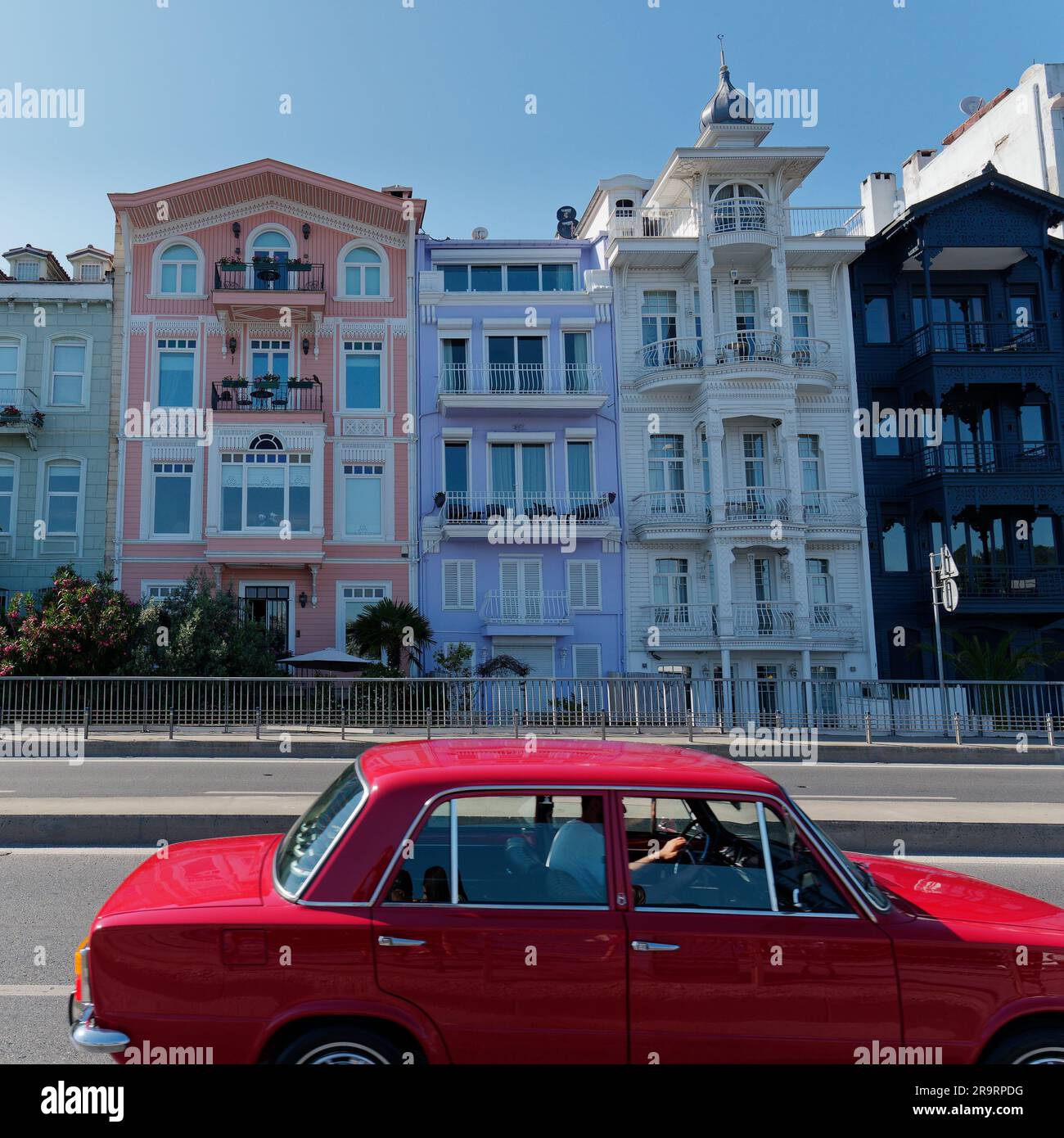 Red Car drives past quaint properties in the neighbourhood of Bebek Istanbul, Turkey Stock Photo