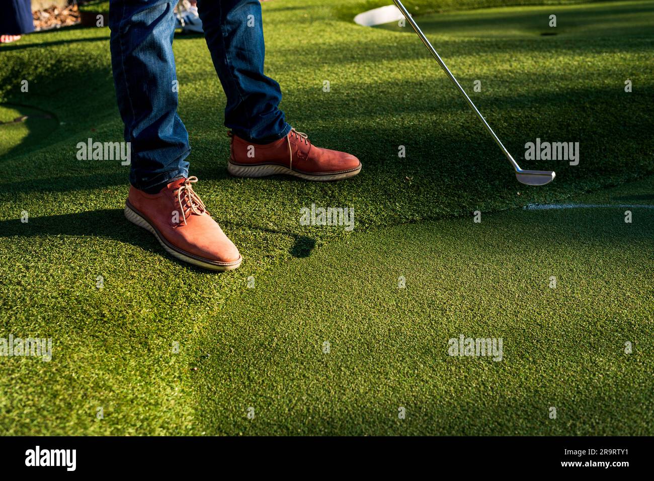 photo of man in brown shoes is playing golf on lawn Stock Photo