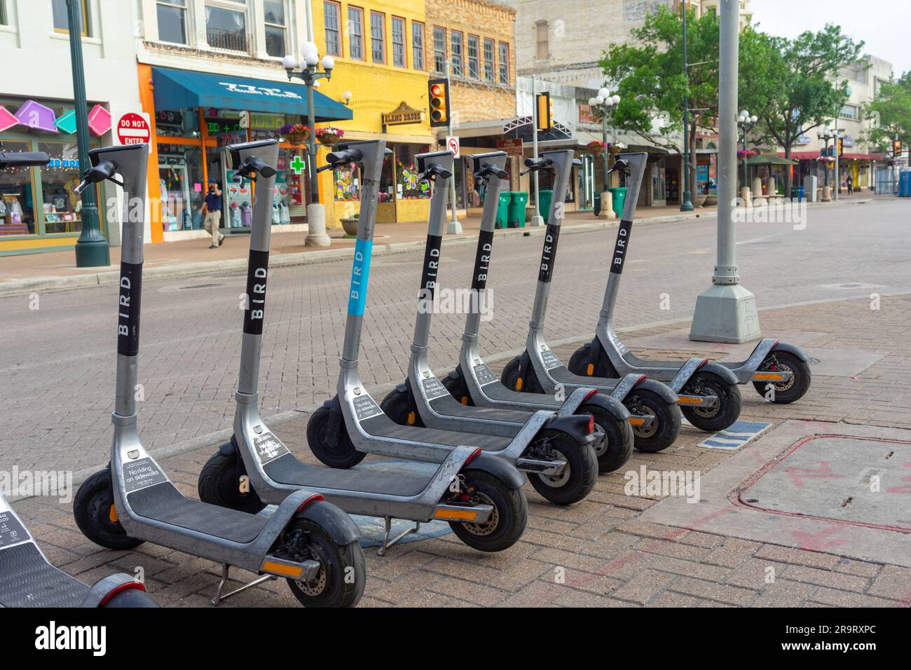 San Antonio, Texas, USA – May 8, 2023: A row of Bird electric ride share scooters parked on a sidewalk in downtown San Antonio, Texas. Stock Photo