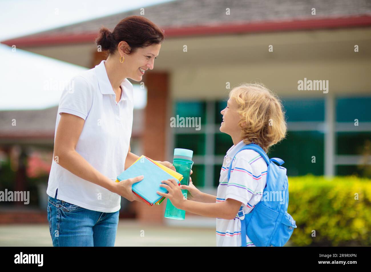 Mother bringing child to school. Parents pick up little boy after class