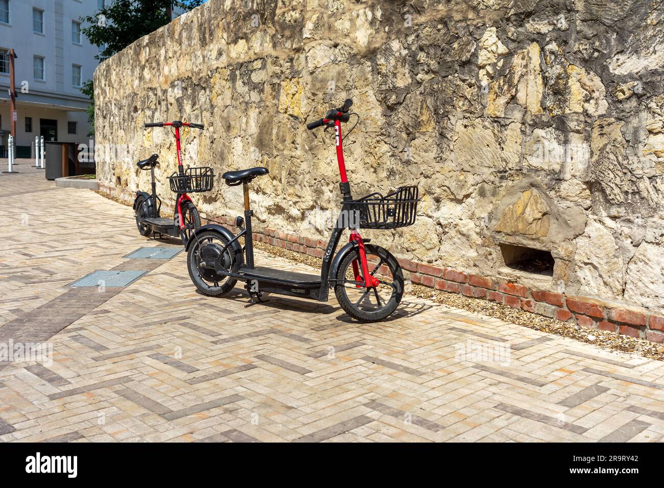 San Antonio, Texas, USA – May 8, 2023: A Razor electric ride share scooters with a seat and basket parked on a sidewalk in downtown San Antonio, Texas Stock Photo