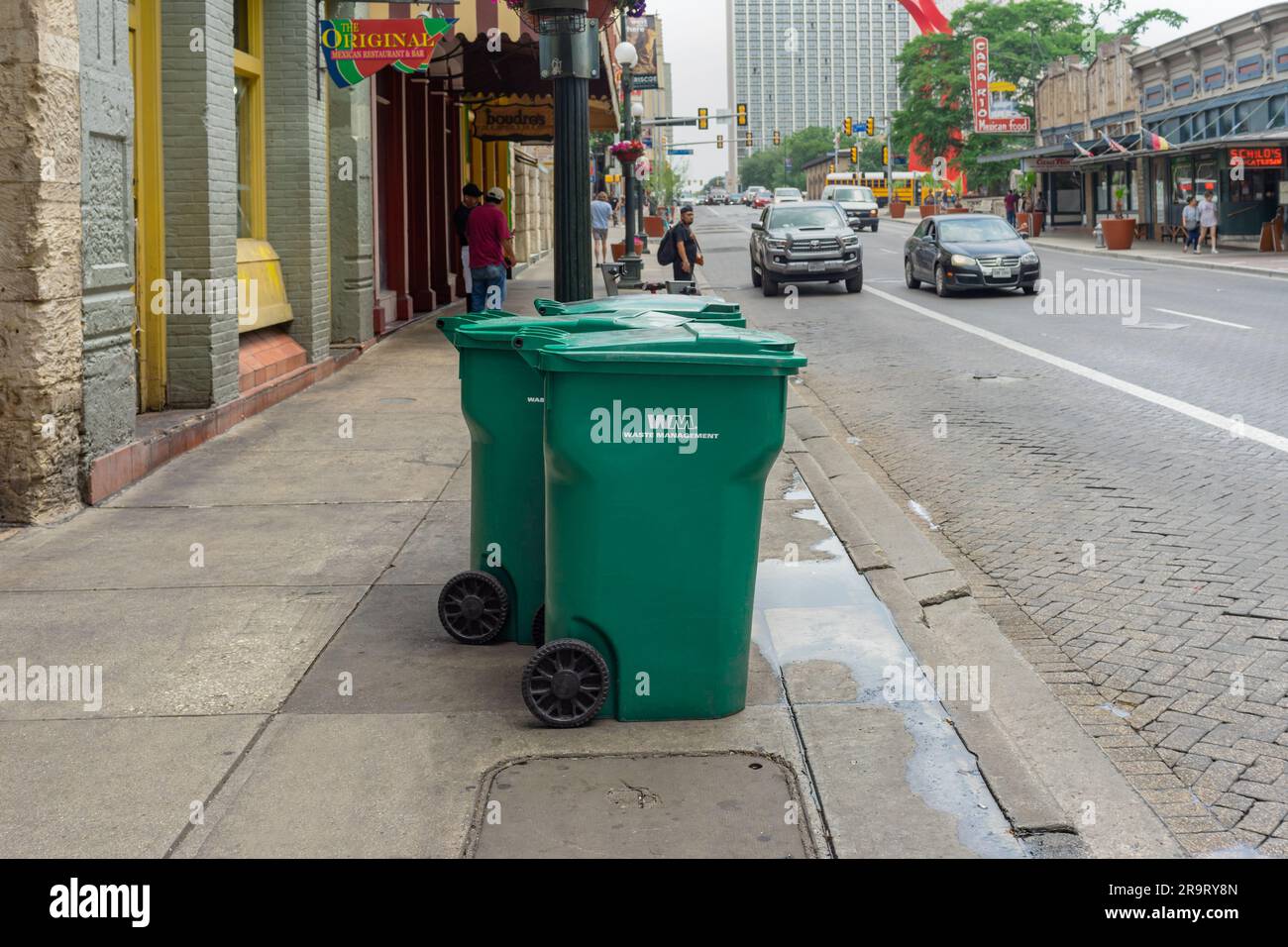 San Antonio, Texas, USA May 8, 2023 Green garbage bins placed at curbside on a street in
