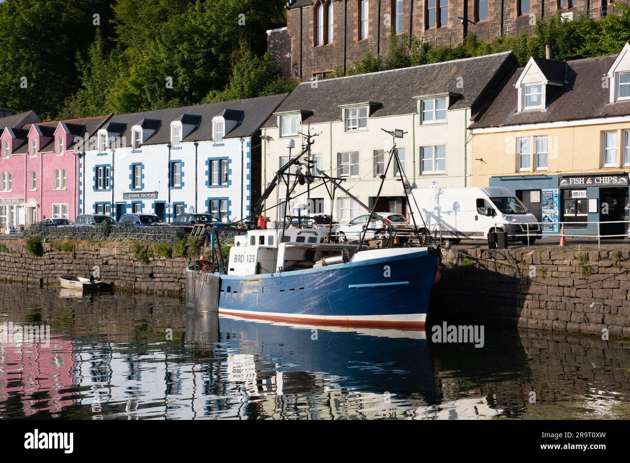 A Fishing Vessel (Dunan Star II) Moored at the Quayside in Portree Harbour, Isle of Skye, in Front of the Brightly Coloured Buildings on Quay Street. Stock Photo