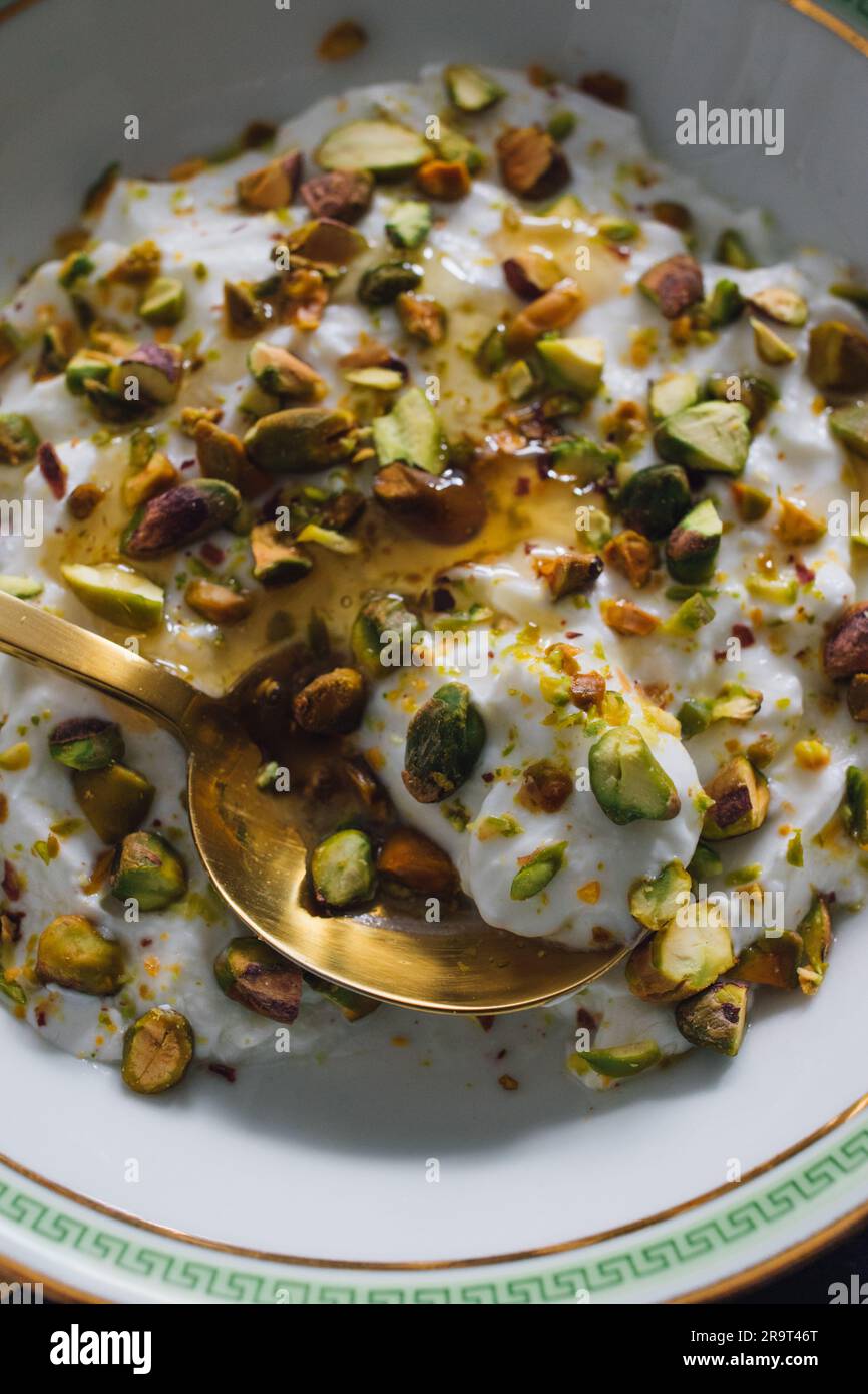 greek yogurt with green pistachios and honey drizzle in white, green