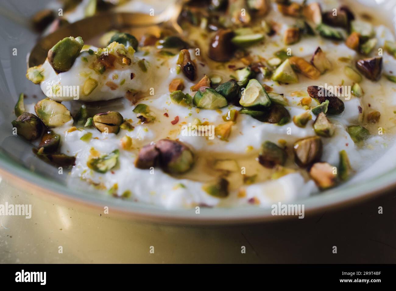 greek yogurt with green pistachios and honey drizzle in white, green