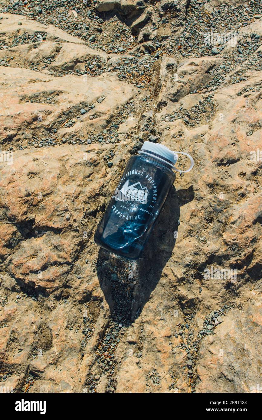 blue REI Nalgene water bottle outdoors on rock in the sun while hiking Stock Photo