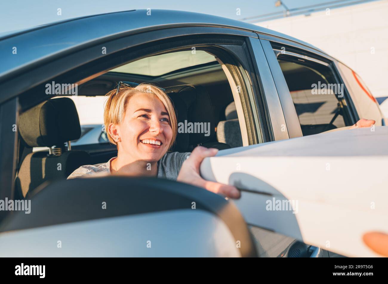 Young female sitting in car driver seat and sincerely smiling to