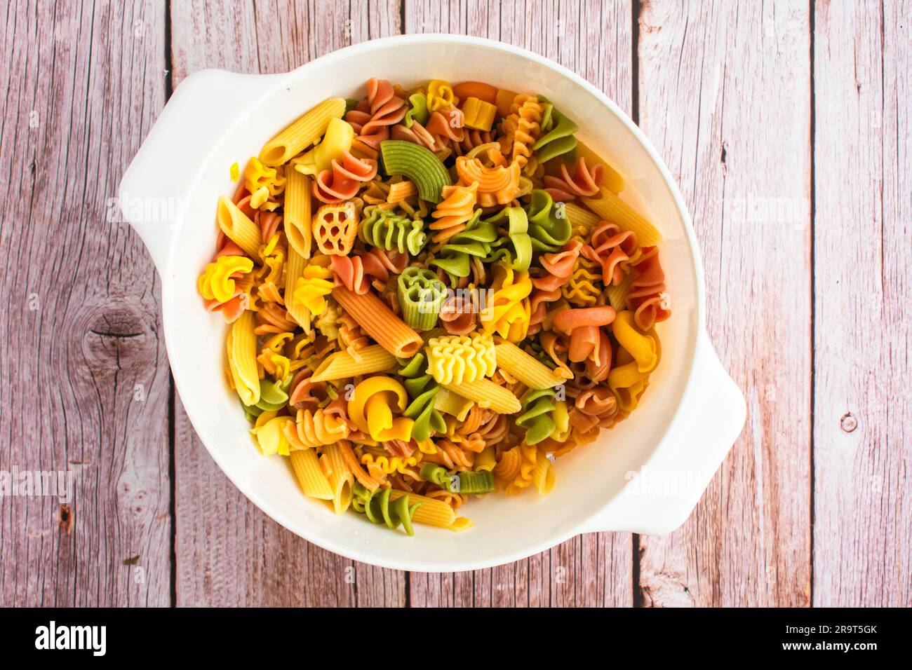Tricolor Pasta Drained in a Large Colander: Overhead view of various tri color pasta shapes in a plastic strainer Stock Photo