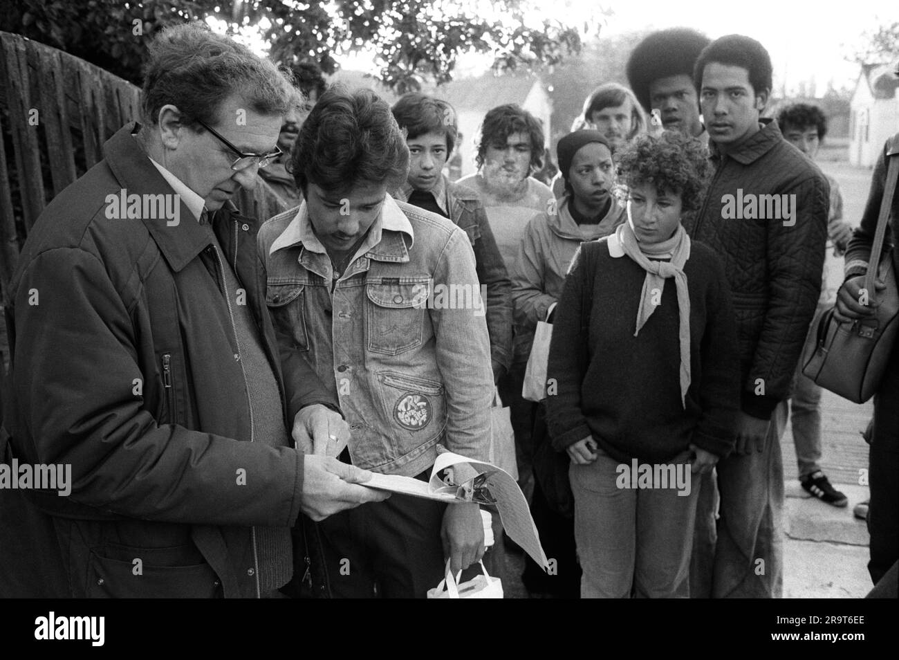 Foreign overseas students seasonal fruit picking. A farmer is checking names from a register of student pickers before they get on a lorry that takes them out to the apple orchard. Wisbech, Cambridgeshire, England circa 1977. 1970S UK HOMER SYKES Stock Photo