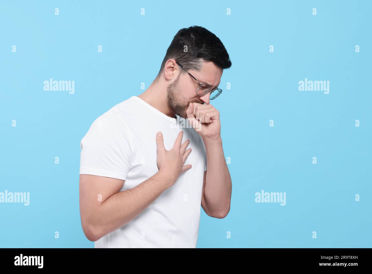 Man coughing on light blue background. Sore throat Stock Photo Alamy