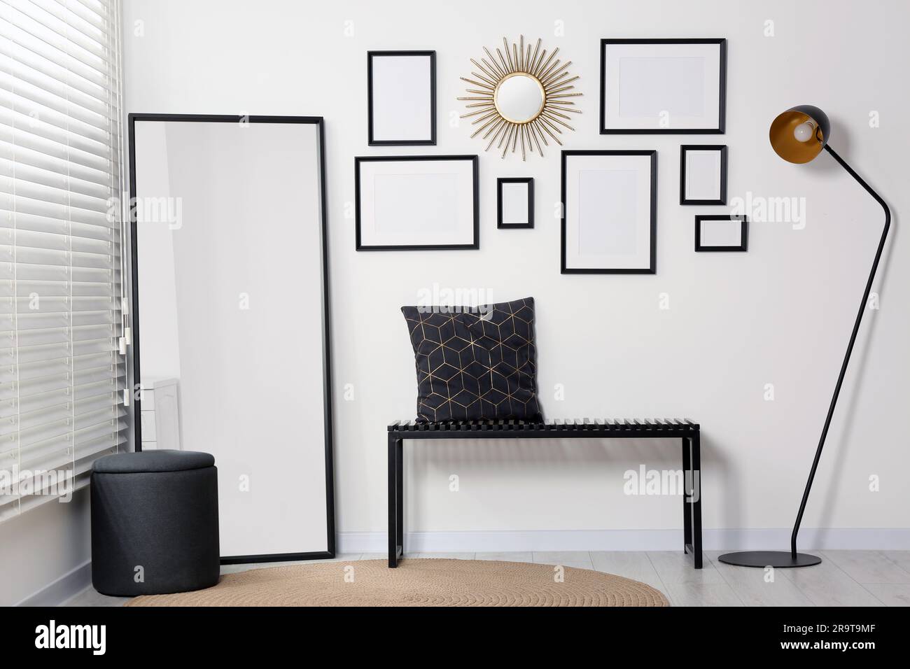 Stylish room interior with empty frames hanging on white wall and