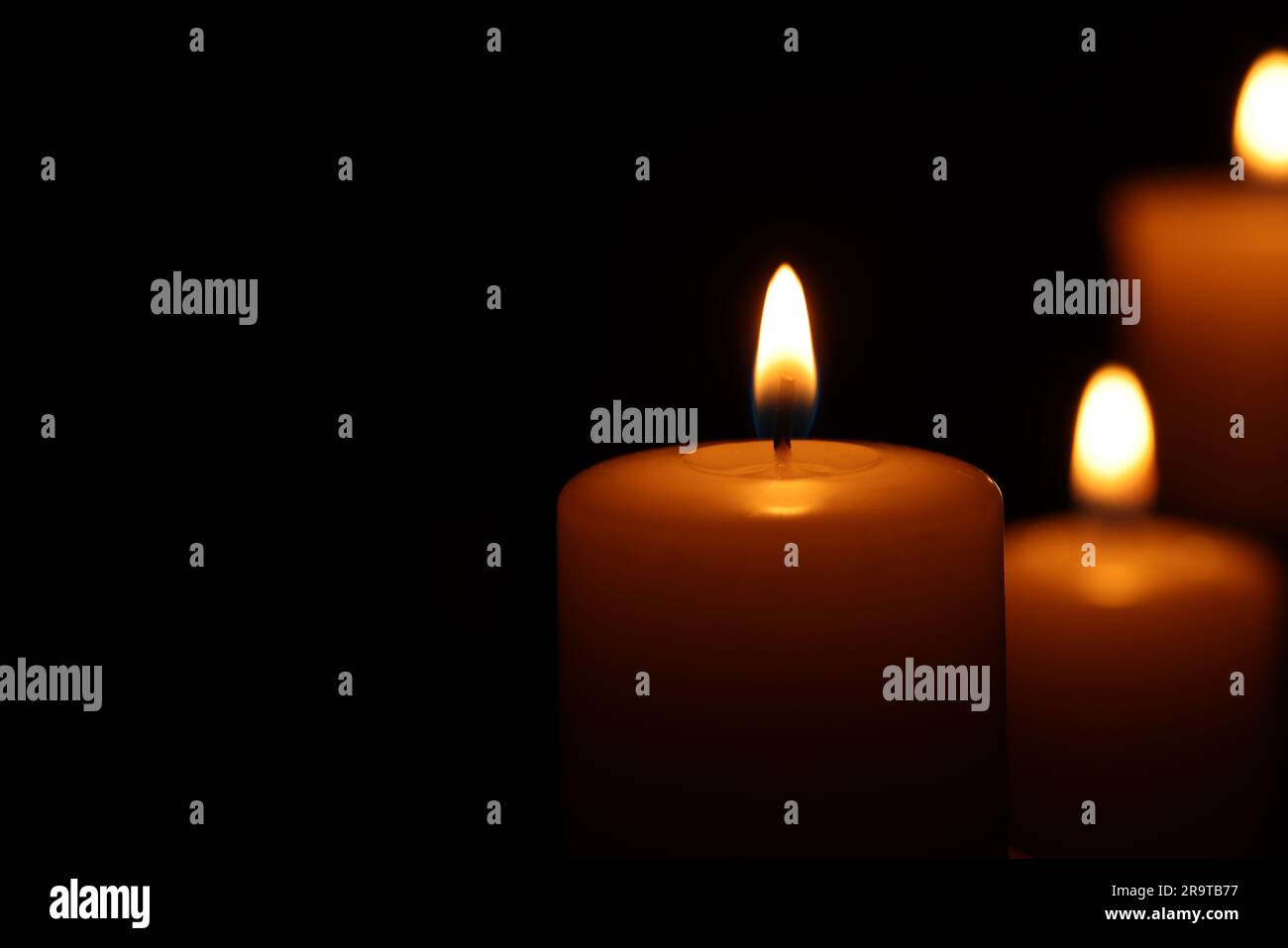 Burning wax candles on black background, closeup. Space for text Stock ...