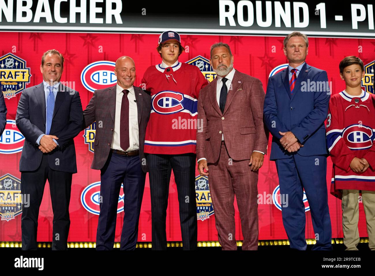 David Reinbacher, center, poses with Montreal Canadiens officials after