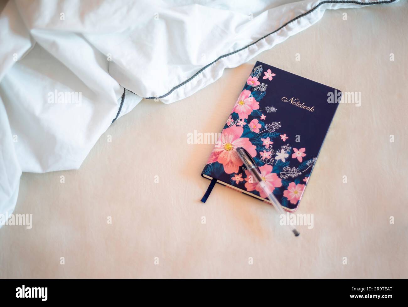Colourful notebook and pen lying in bed Stock Photo