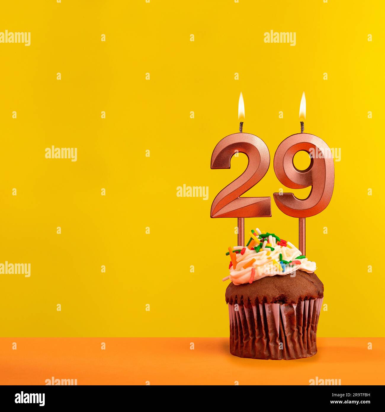 Candle with flame number 29 - Birthday card on yellow background Stock Photo
