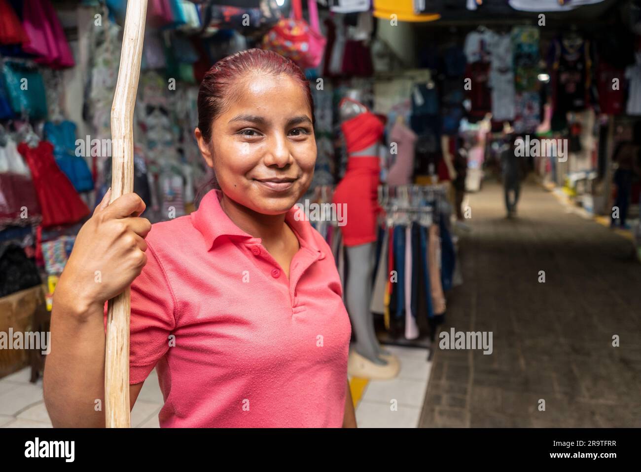 Retailer in front of a stretch of clothing with a wooden stick to place garments at a traditional market in Nicaragua Stock Photo