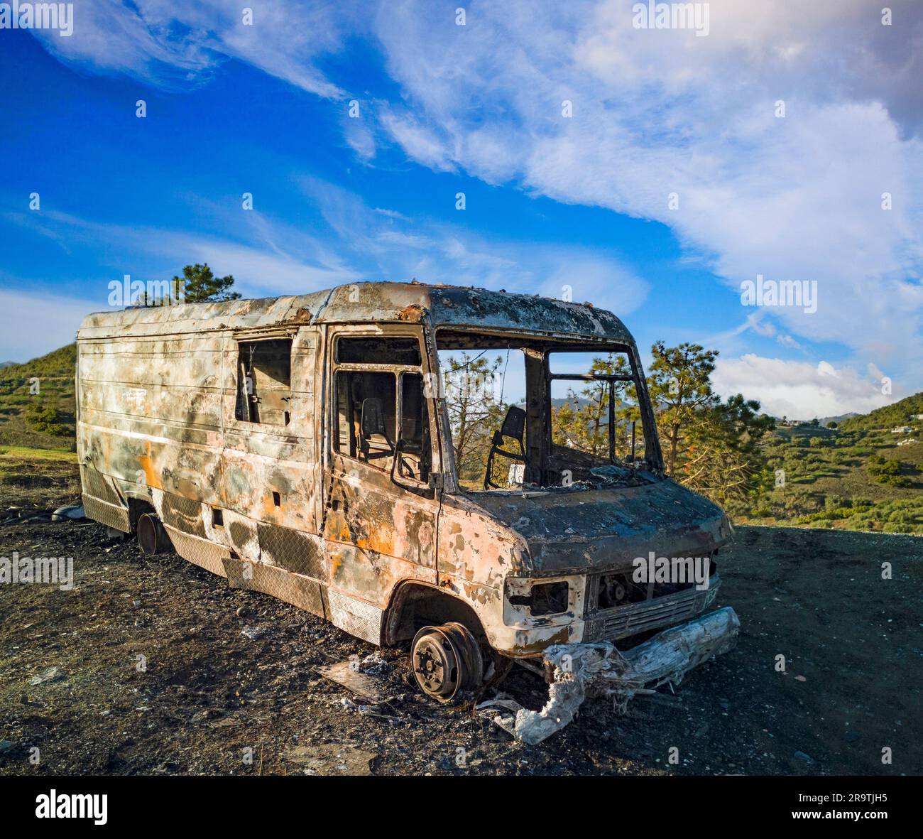 Remains of burnt van left in nature Stock Photo