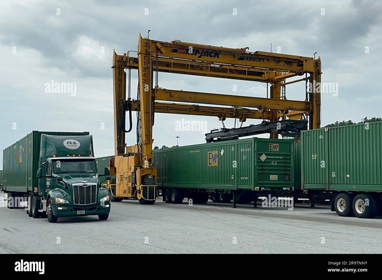 A truck pulls a trailer loaded with a shipping container away from a ...