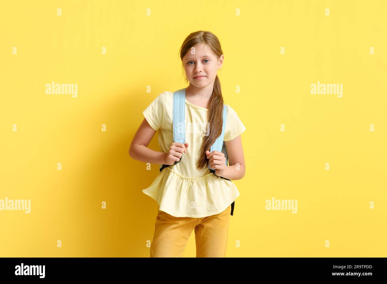 Little girl with backpack on yellow background Stock Photo - Alamy