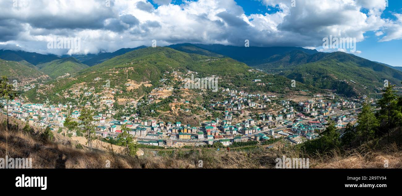 South Thimphu's panoramic view showcases lush green hills, meandering rivers, and towering mountains, adorned with vibrant prayer flags fluttering aga Stock Photo