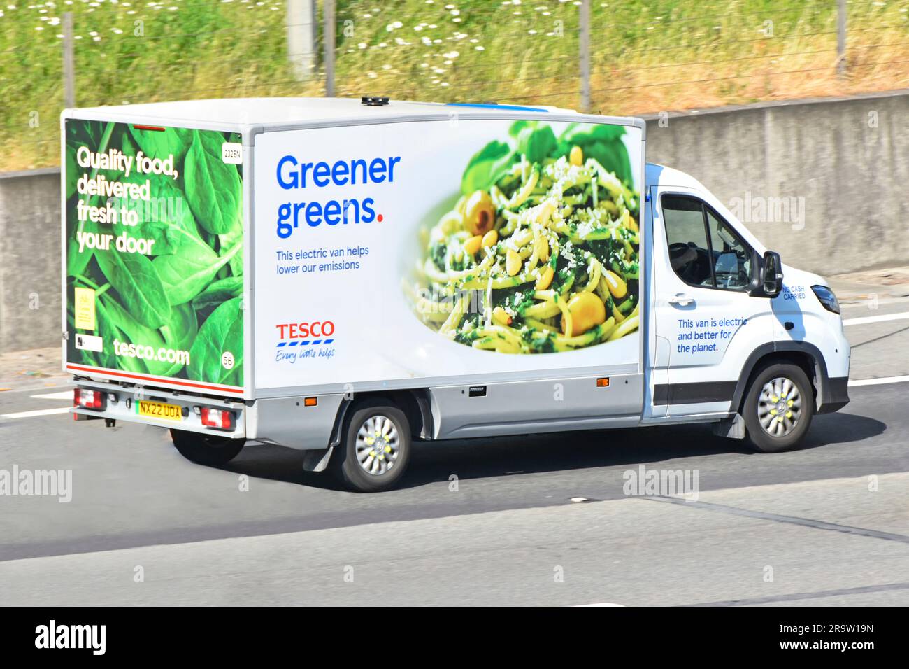 Electric powered Tesco supermarket food supply chain retail business delivery of online grocery shopping order by van driving on M25 motorway road UK Stock Photo