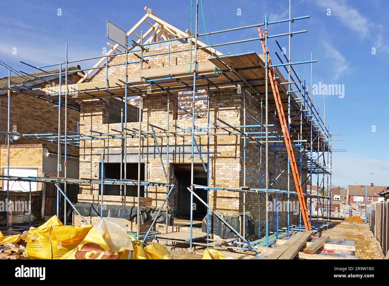New build detached residential property with superstructure brick walls progressing at gable end with timber roof trusses fixed in position England UK Stock Photo