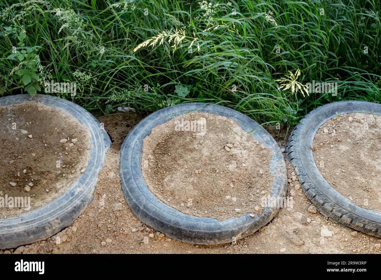 Old tires filled with rammed earth, used for house footing or ground stabilisation. Stock Photo