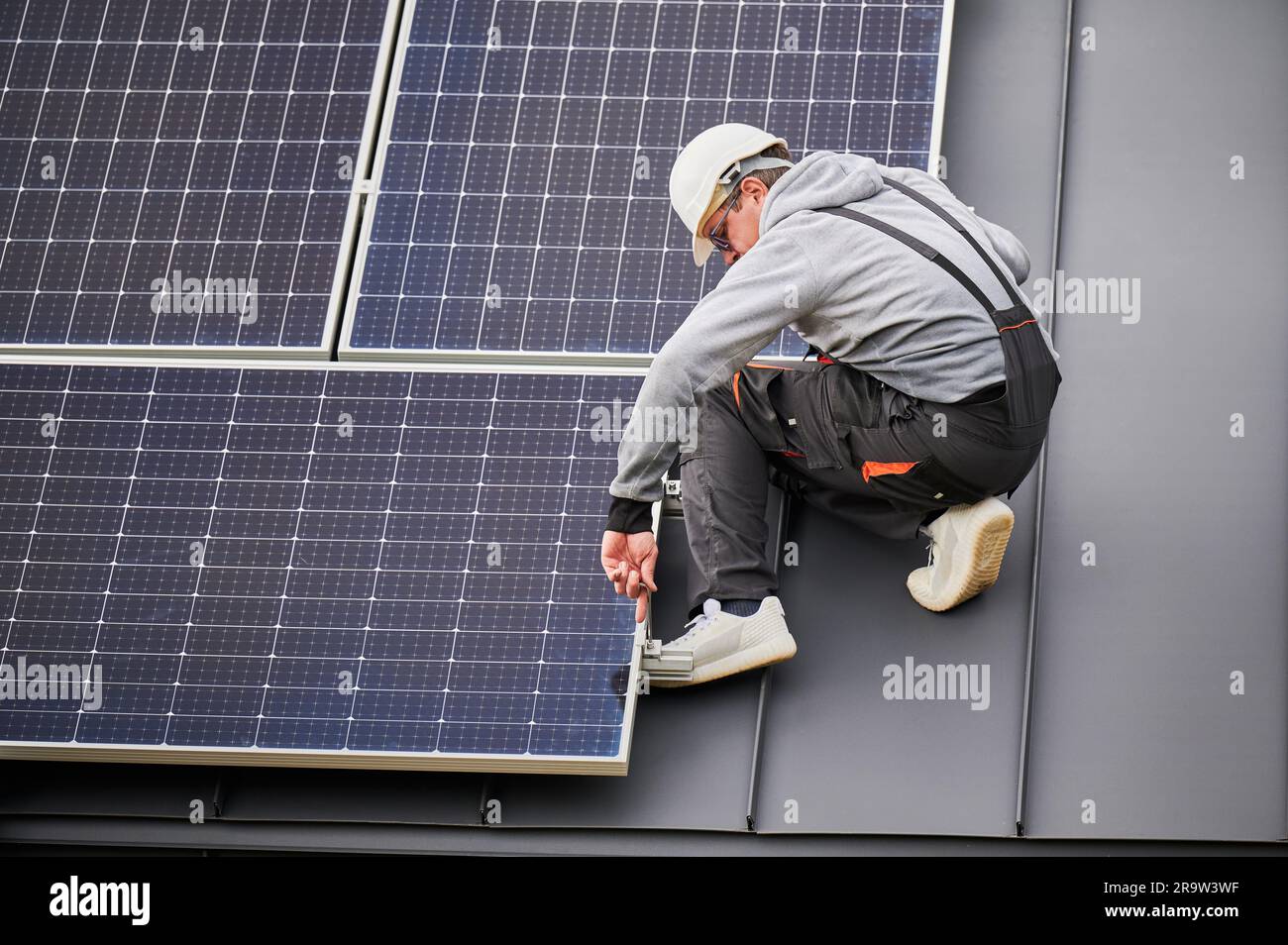 Man technician mounting photovoltaic solar panels on roof of house