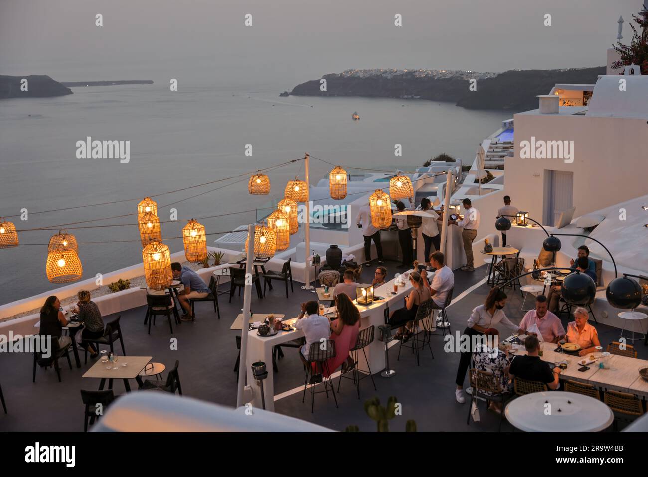 Imerovigli, Santorini, Greece - July 1, 2021: People having a romantic dinner on the panoramic terrace of a restaurant in Imerovigli, Santorini. Greec Stock Photo