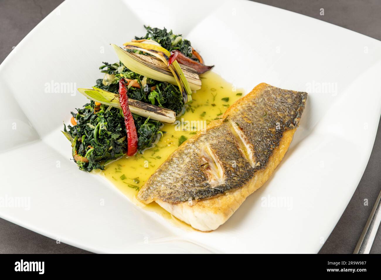 Grilled sea bass fillet served with garnishes in a fine dining restaurant Stock Photo