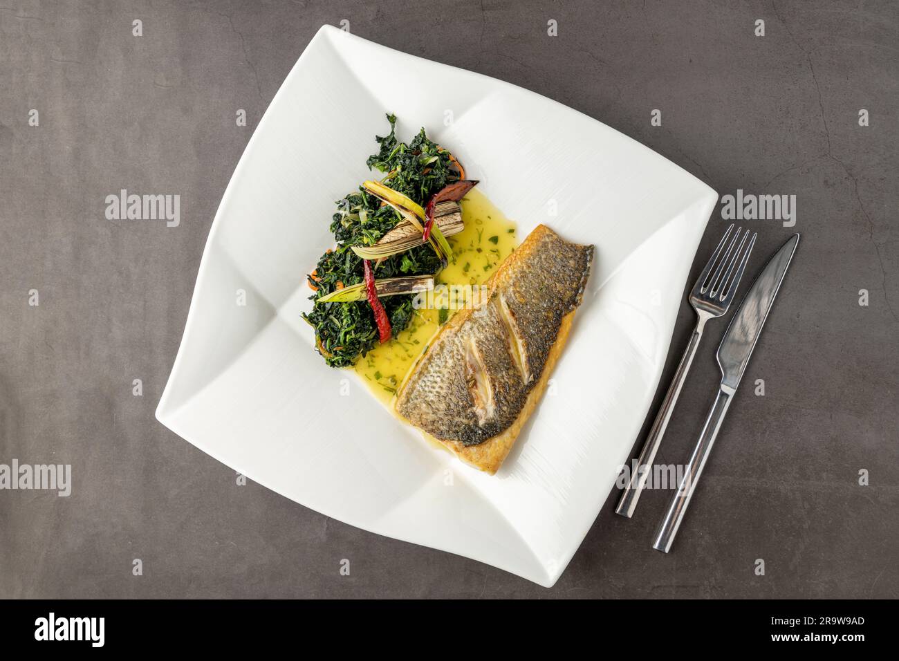 Grilled sea bass fillet served with garnishes in a fine dining restaurant Stock Photo