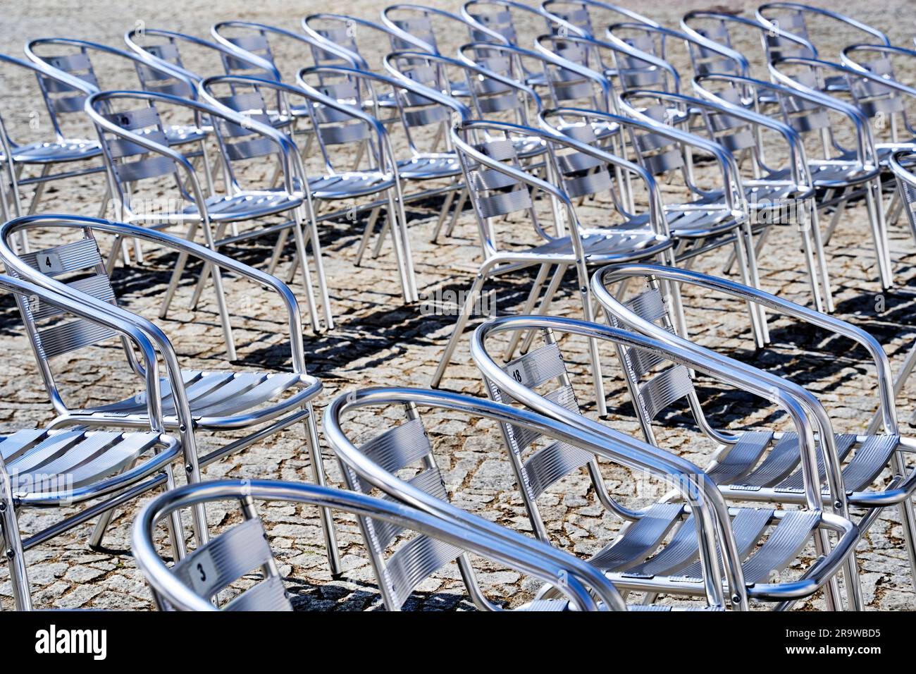 Empty aluminum chairs on cobblestones in sunshine Stock Photo Alamy