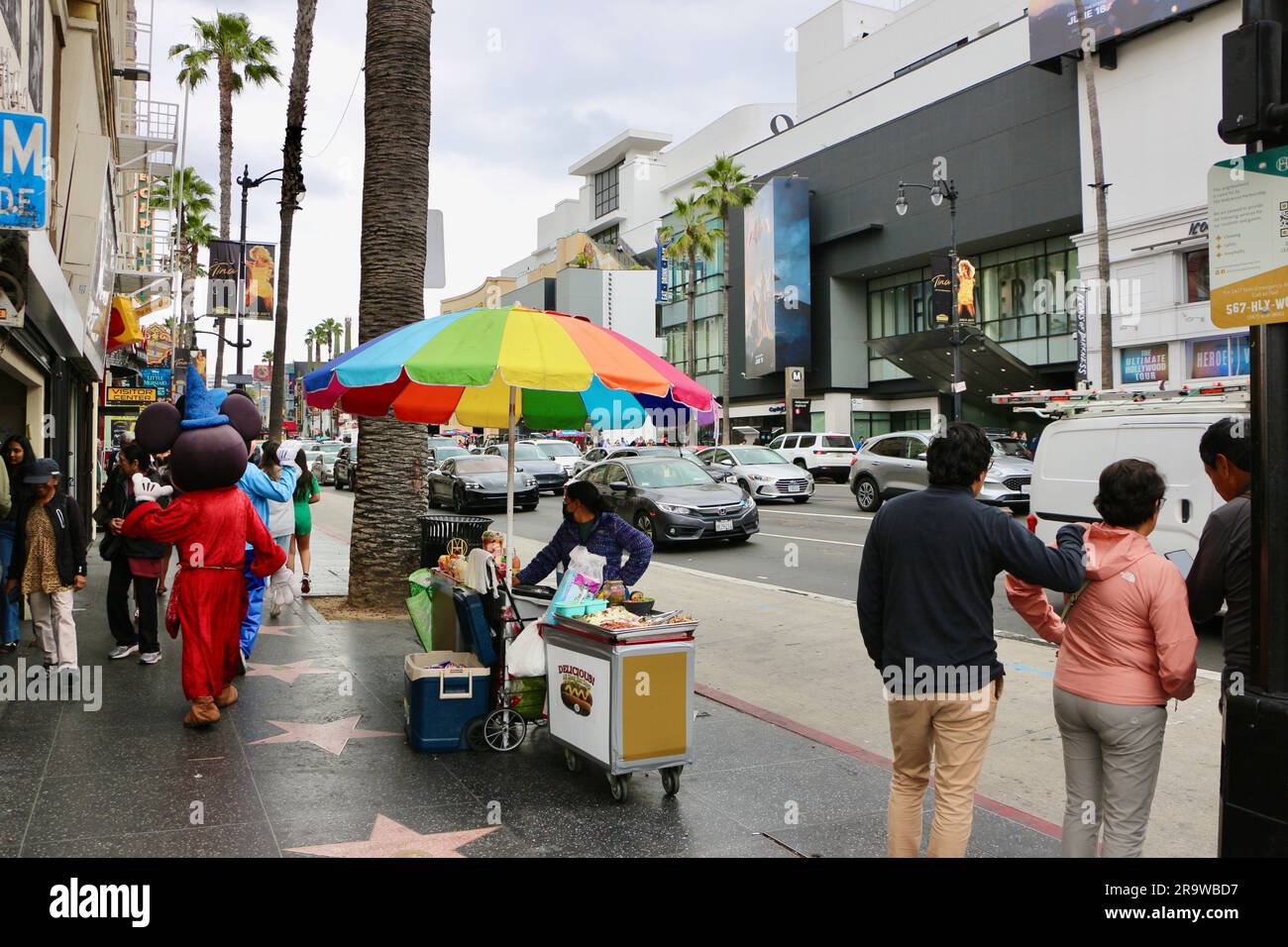 All meat hot dog stand with a rainbow umbrella and passing Mickey Mouse Hollywood Boulevard Los Angeles California USA Stock Photo